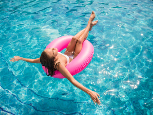Young woman relaxing in her backyard pool