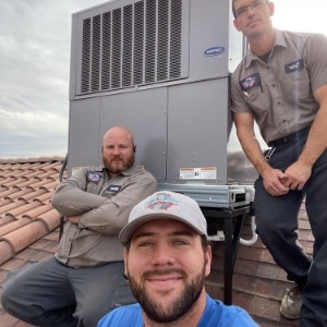 workers standing by newly installed HVAC unit on roof