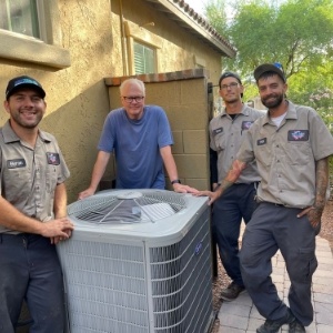 workers standing with homeowner by new HVAC unit they installed in his backyard